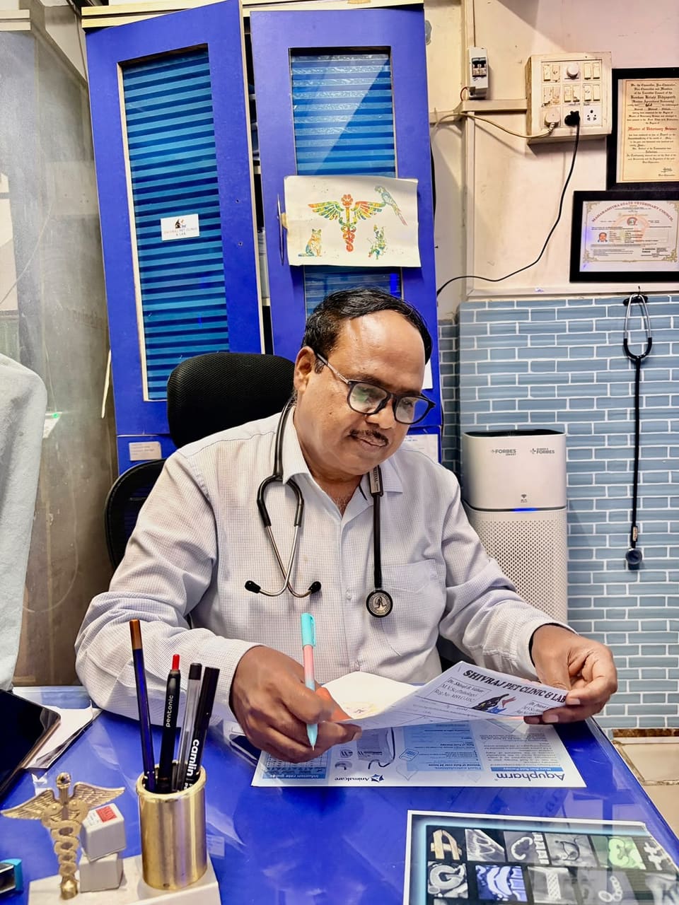 Dr. Shivaji Vidhate at his consultation desk writing a prescription