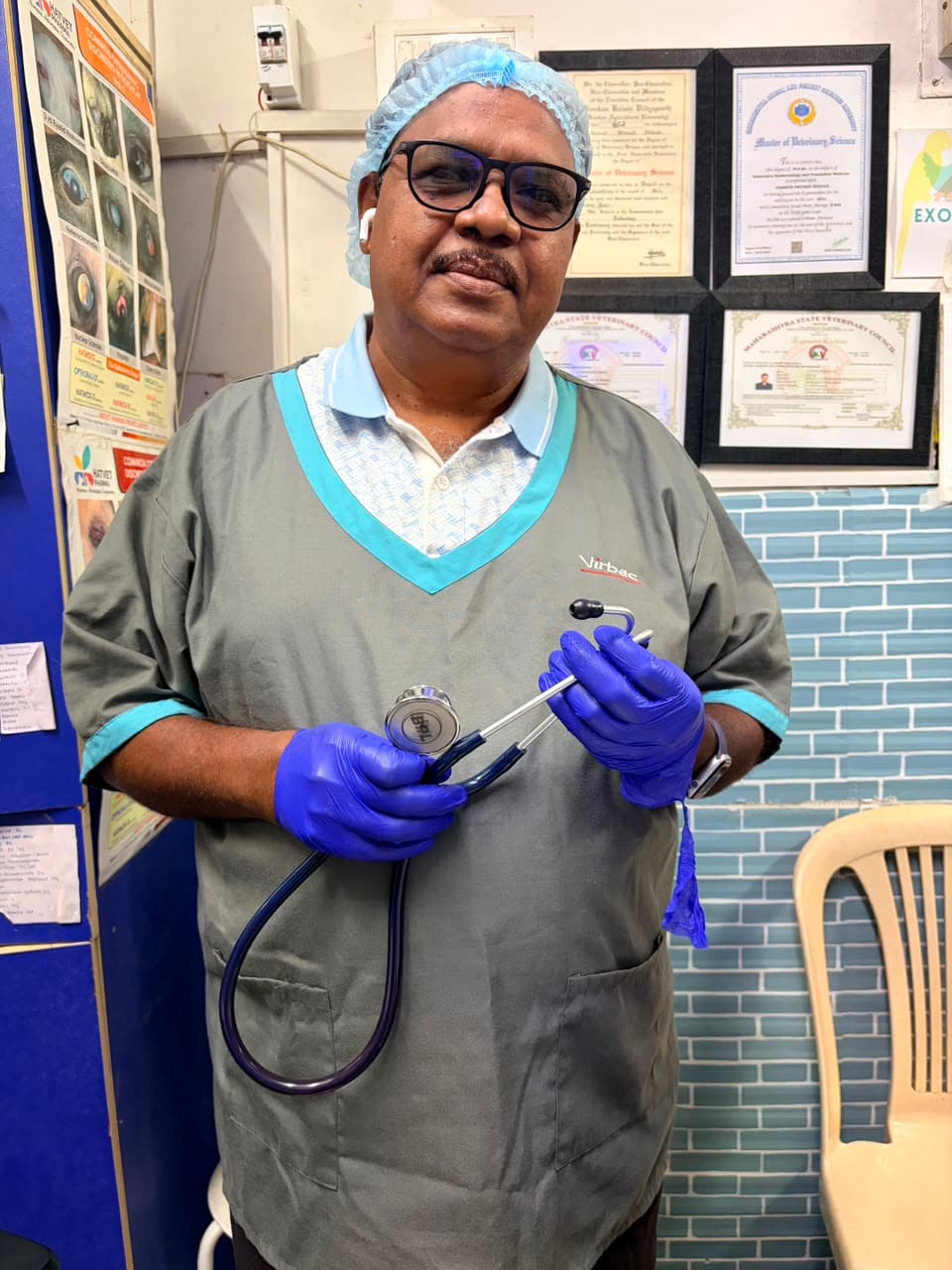 Dr. Shivaji Vidhate in a surgical cap with his veterinary degree certificate behind him